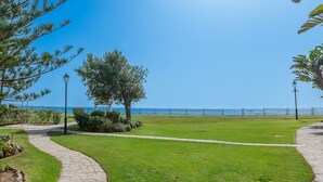 Ein Weg führt zu einer Wiese mit Blick auf das Meer und einem Zaun.