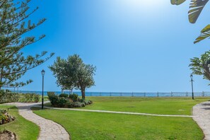 Un sentier qui mène à une zone herbeuse offrant une vue sur la mer et bordée d’une clôture.