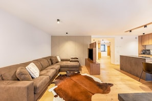A modern living room with a sectional sofa, a television, and a unique cowhide rug.