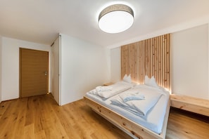Un dormitorio moderno con cama de madera, cabecera integrada y lámpara de techo.