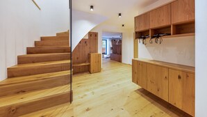 A wooden staircase leading to a second floor, a wooden cabinet with hooks, and a hallway with a wooden floor. - UB31 Holiday Apartment – Exclusive Apartment with Private Wellness Oasis (Deutschnofen)