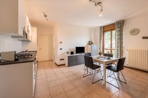 Une cuisine moderne avec un coin repas, un téléviseur et une horloge au mur.