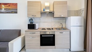 Eine kleine Küche mit Mikrowelle, Herd, Backofen und Kühlschrank.