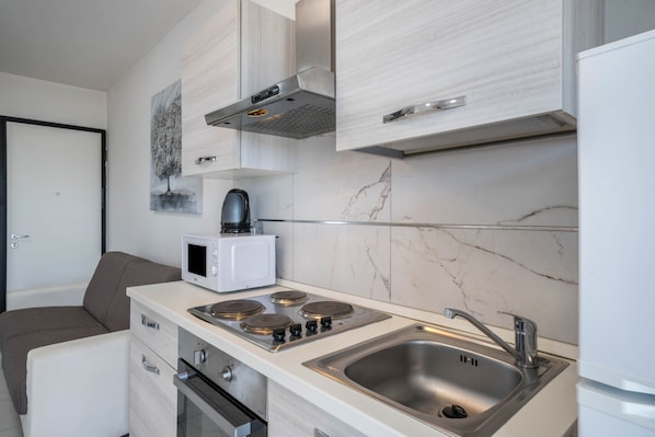 A compact kitchen with a microwave, stove, and sink.