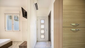 A hallway with a bed, a TV, a wardrobe, and a door. - Holiday Apartment "Residenza Maja 6" with Wi-Fi (San Michele al Tagliamento)