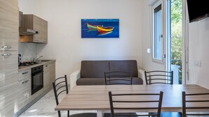A modern kitchen with wooden cabinets, a dining table with chairs, and a painting of a boat on the wall. - Holiday Apartment "Residenza Maja 6" with Wi-Fi (San Michele al Tagliamento)