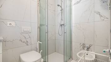 Une salle de bain avec une douche à parois de verre, des toilettes et un bidet.