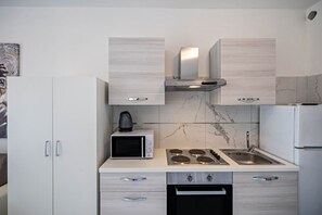 A compact kitchen with a microwave, stove, sink, and cabinets.