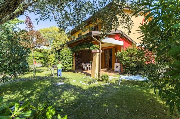 Une maison avec un patio couvert, un lave-linge et un enfant qui joue dans la cour.