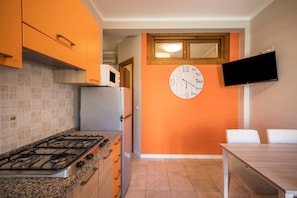 Une cuisine équipée d’une cuisinière à gaz, d’un four à micro-ondes et d’une horloge murale.