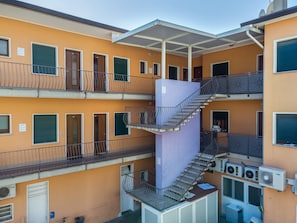A multi-story building with balconies, a central stairwell, and air conditioning units.