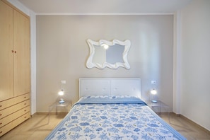 A bedroom with a bed, a wardrobe, a mirror, and bedside lamps.
