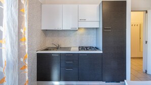 Une cuisine moderne avec des meubles hauts blancs, des meubles bas foncés, un évier en acier inoxydable et une cuisinière à gaz.
