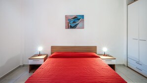 Une chambre à coucher avec une tête de lit en bois, une couvre-lit rouge, deux tables de chevet avec des lampes et un tableau au mur.