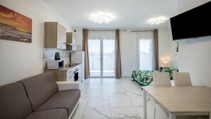 Ein modernes Wohnzimmer mit Sofa, Esstisch und Küchenzeile inklusive Mikrowelle.