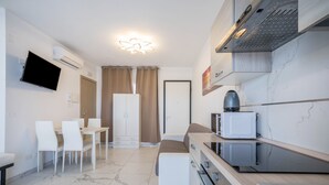 Eine moderne Küche mit Einbauofen, Mikrowelle und Spüle. Es gibt einen Essbereich mit Tisch und Stühlen sowie einen an der Wand befestigten Fernseher.