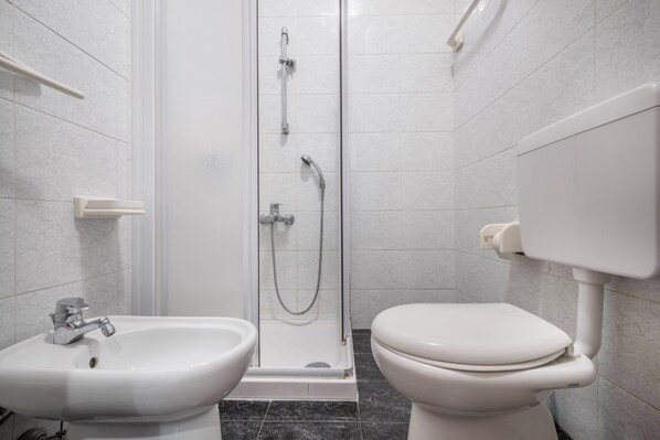 Une salle de bain avec une douche, deux lavabos et des toilettes.