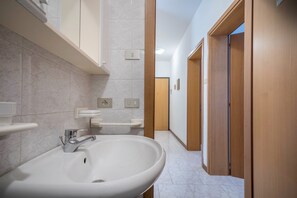 A modern bathroom with a large sink, mirror, and towel rack. - Appartamento della Bilancia 4 (Bibione)