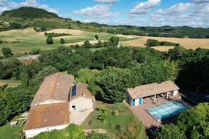 Une maison de campagne dotée d’un panneau solaire, d’une piscine et d’un petit bâtiment surmonté d’un toit bleu.