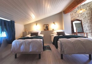 A bedroom with two beds, a wooden ceiling, a stone wall, and a mirror. - Residence La Borde (Plavilla)