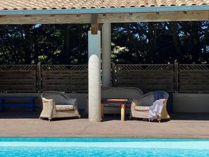 A poolside area with two wicker chairs, a small table, and a bench. - Residence La Borde (Plavilla)