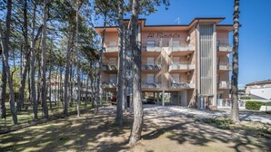 A multi-story hotel named 'Al Boschetto' with a central courtyard, surrounded by trees. - Appartamento Andromeda 13 (Bibione)