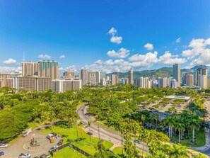 A cityscape with high-rise buildings, a green park area, and a clear sky.