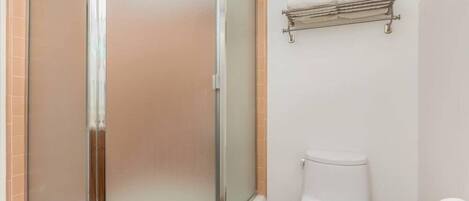 A bathroom with a glass-enclosed shower, a white toilet, and a towel rack on the wall.