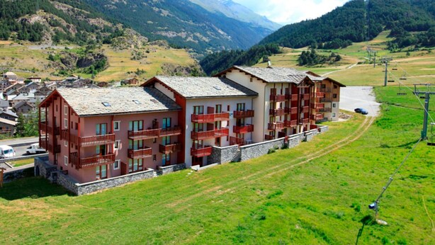 A multi-story hotel with balconies, set in a mountainous area with a clear sky. - Cozy 4-Person Ski-in/Ski-out Apartment with Balcony, Free WiFi, and Garage in Val Cenis (Termignon)