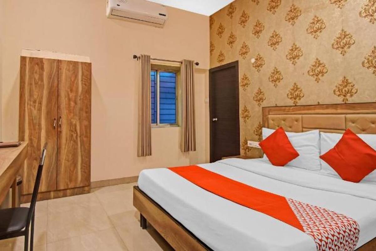 Habitación de hotel con cama, escritorio, silla, armario y televisor.