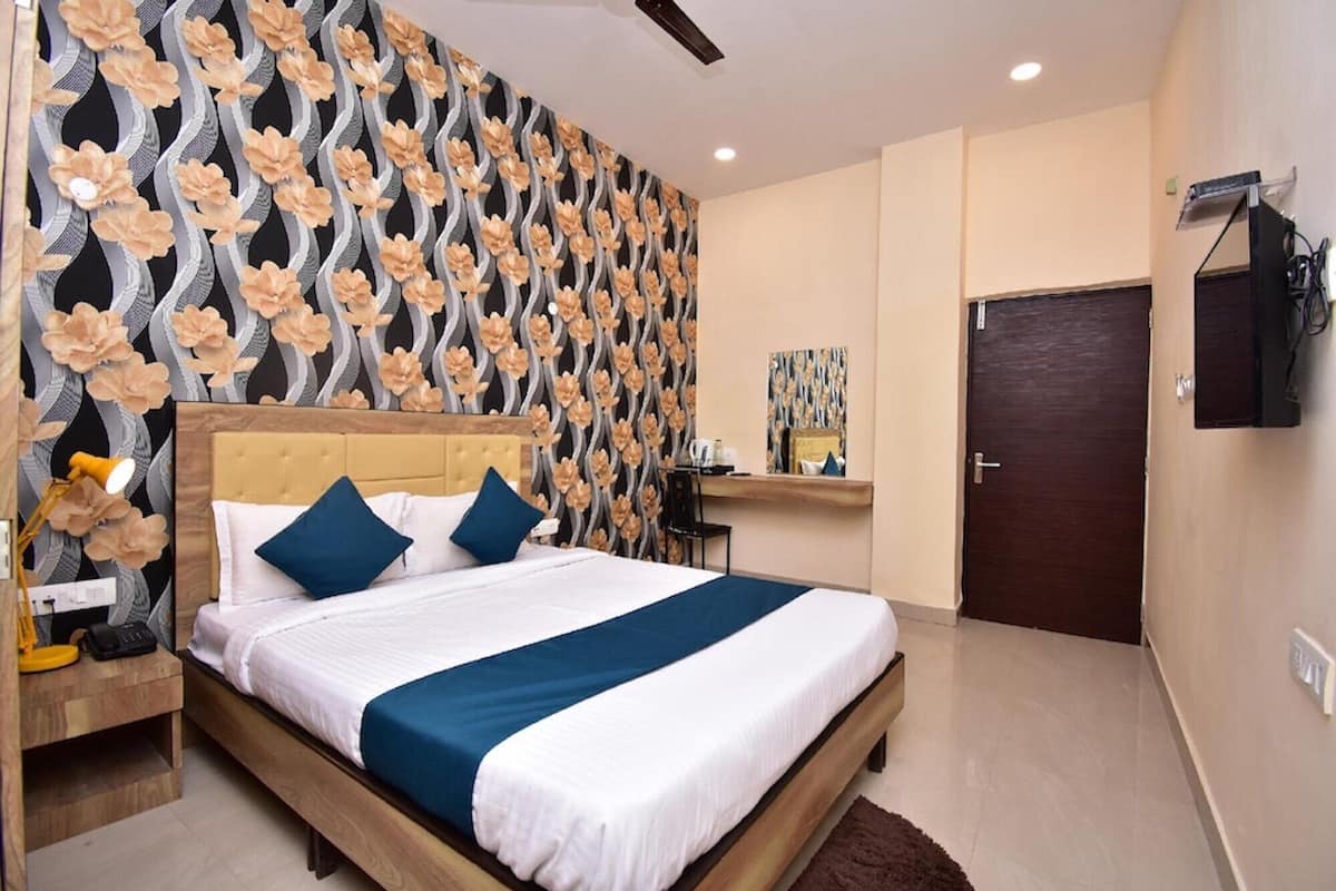 Habitación de hotel con cama, escritorio, silla, televisor y puerta.