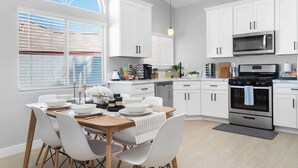 A modern kitchen with white cabinets, a black microwave, and an oven. - Modern 3 BR Home w/ Hot Tub, Pool, Golf! (North Las Vegas)