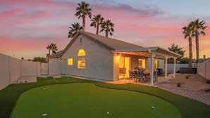 A house with a covered patio, a small lawn, and palm trees. - Modern 3 BR Home w/ Hot Tub, Pool, Golf! (North Las Vegas)
