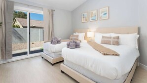 A hotel room with two beds, a sliding glass door to the outside, and a view of a house. - Modern 3 BR Home w/ Hot Tub, Pool, Golf! (North Las Vegas)