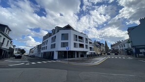 A multi-story building with a modern design, featuring a prominent entrance and a visible ground floor with a sign.