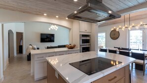 Una cocina moderna con una isla central, horno integrado y un ventanal grande.