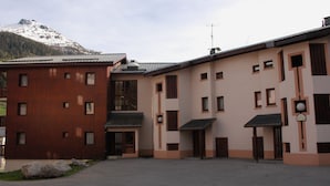 Un edificio con fachada roja y otra fachada color beige, ambos con numerosas ventanas y techo plano.