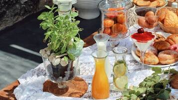 Una mesa al aire libre con diversos alimentos, una vela y una planta en maceta.