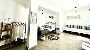 Zona d'estar àmplia amb sofà, llit i taula petita. Hi ha elements decoratius a prestatges i un prestatge fixat a la paret.