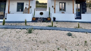Una casa moderna de dos pisos amb façana blanca, bigues de fusta i una paret de pedra al costat dret.