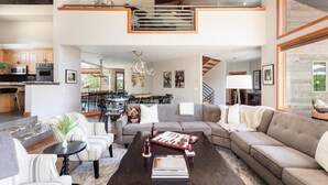 A spacious living area with a large sofa, a coffee table, and a dining area with chairs and a table. - Nansen Villa (Park City)