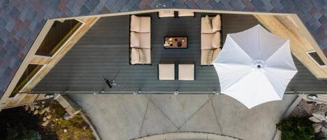 Une terrasse sur le toit, aménagée avec un espace salon, une table et un grand parasol.