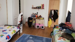 A room with two beds, a desk with various items, a door, and a wall with shelves. - Spacious 120 m2, 4 bedrooms with garages and Saône view. (Lyon)