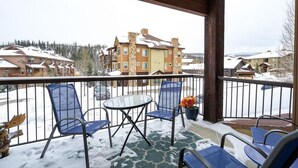 Ein Balkon mit Stühlen und Tisch, Blick auf ein schneebedecktes Gebäude und einen klaren Himmel.