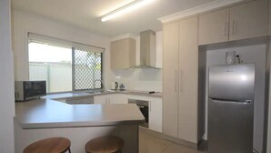 Una cocina moderna con una isla central, refrigerador de acero inoxidable y muebles blancos.