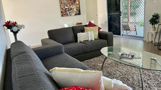 Una sala de estar moderna con un sofá gris, una mesa de centro de vidrio y un cuadro en la pared.