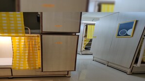 Un pasillo con varios armarios blancos, algunos con cortinas a cuadros amarillos.