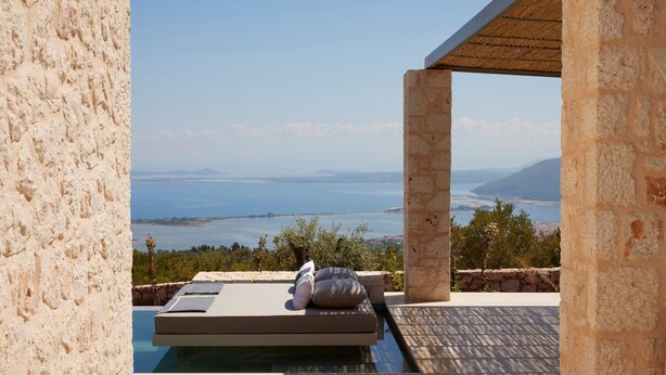 A stone wall with a view of the sea and mountains.