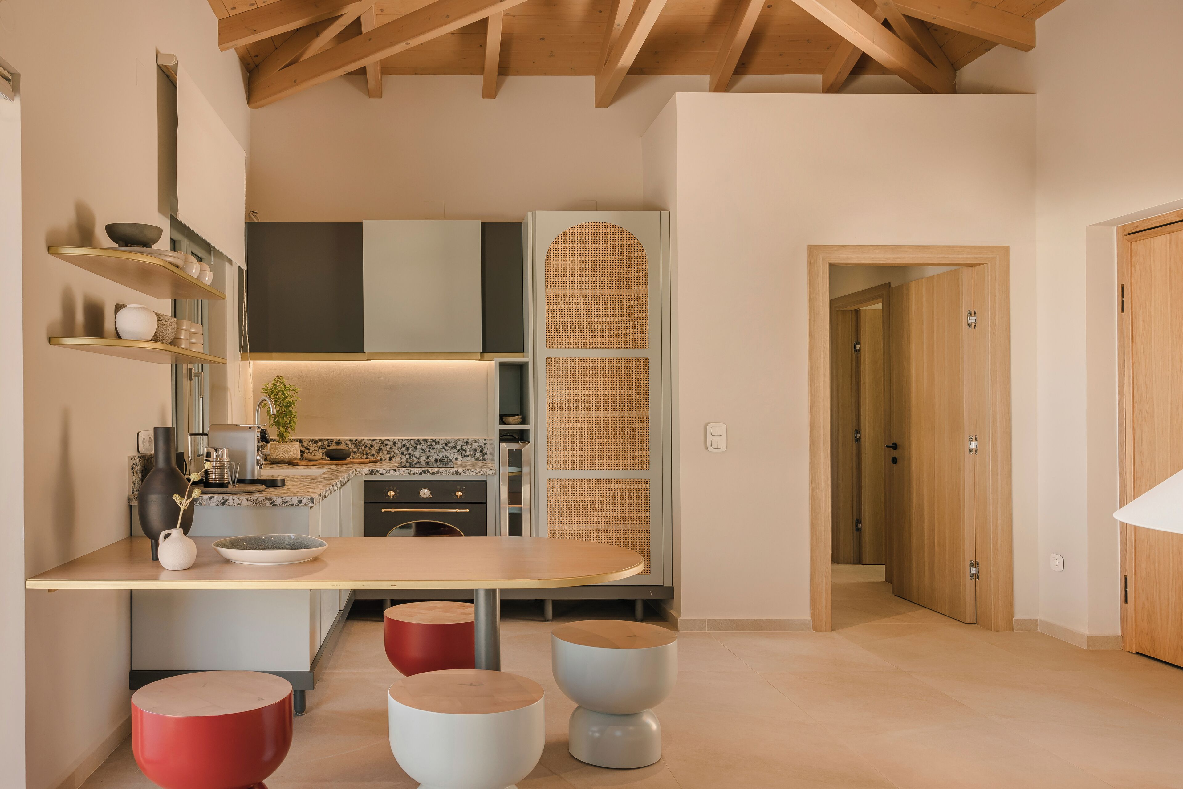 Una cocina moderna con techo de madera, estantes empotrados y una isla central con taburetes.