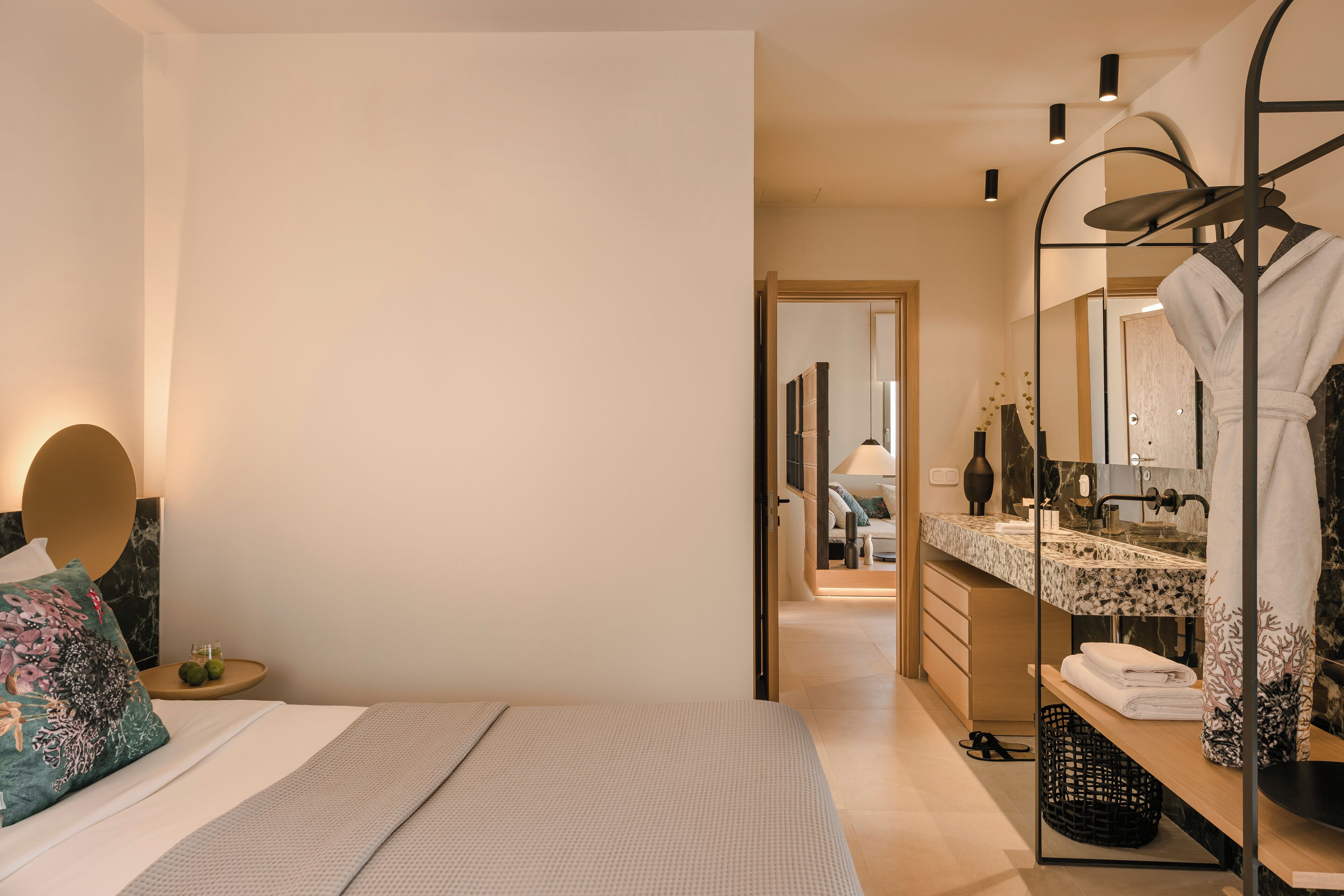Ein modernes Hotelzimmer mit einem großen Bett, einem Badezimmer mit Waschtisch und einem begehbaren Kleiderschrank.